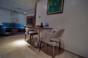 Una sala de estar moderna con un sofá azul, una mesa de comedor con cuatro sillas y un adorno en la pared.