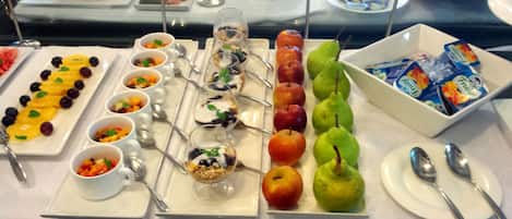 A buffet with various fruits, desserts, and beverages.