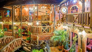 A rustic wooden building with a balcony, brick walls, and potted plants. - Hosteria Jardines de Chamana (Ulba)