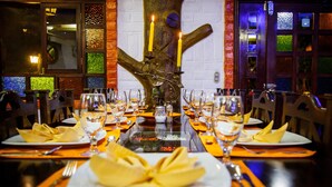 A restaurant with a long table set for a meal, featuring a decorative tree centerpiece with candles. - Hosteria Jardines de Chamana (Ulba)