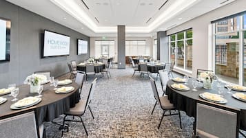 A conference room with tables set for a meeting, a projector screen, and a view of the outside.