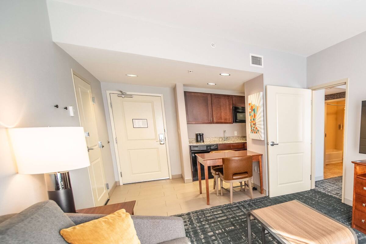 Hotelkamer met een bed, een bureau, een stoel, een lamp, een magnetron en een kitchenette.