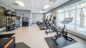 A gym with exercise equipment, a clock, and a window with blinds. - Homewood Suites by Hilton Rochester Mayo Clinic Area / Saint Marys (Rochester)