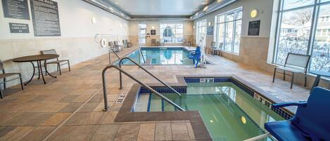 An indoor swimming pool with clear pool rules posted on the wall, a lifeguard chair, and a pool lift sign.