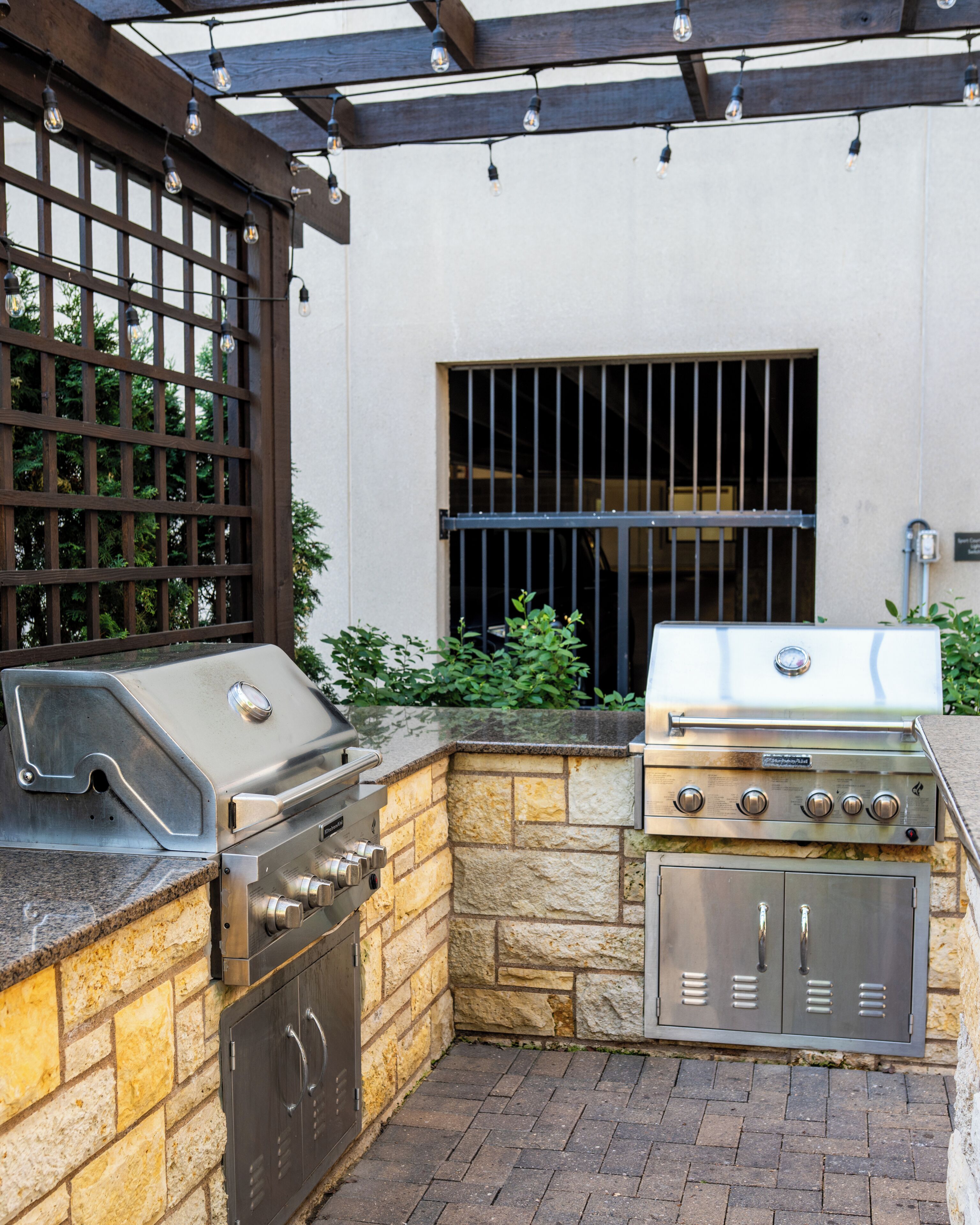 An outdoor kitchen with a grill, a built-in oven, and a stone wall.