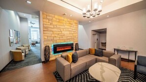 A modern hotel lobby with a stone wall fireplace, comfortable seating, and a chandelier. - Homewood Suites by Hilton Rochester Mayo Clinic Area / Saint Marys (Rochester)