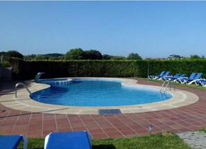 Una piscina al aire libre, tumbonas