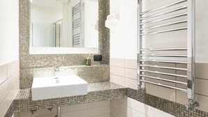 A bathroom with a white sink, a large mirror, and a chrome towel rack. - Cesar Vatican Rooms (Rome)