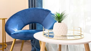 A blue chair with a gold frame, a white table with a gold tray, and a potted plant on the table. - Cesar Vatican Rooms (Rome)