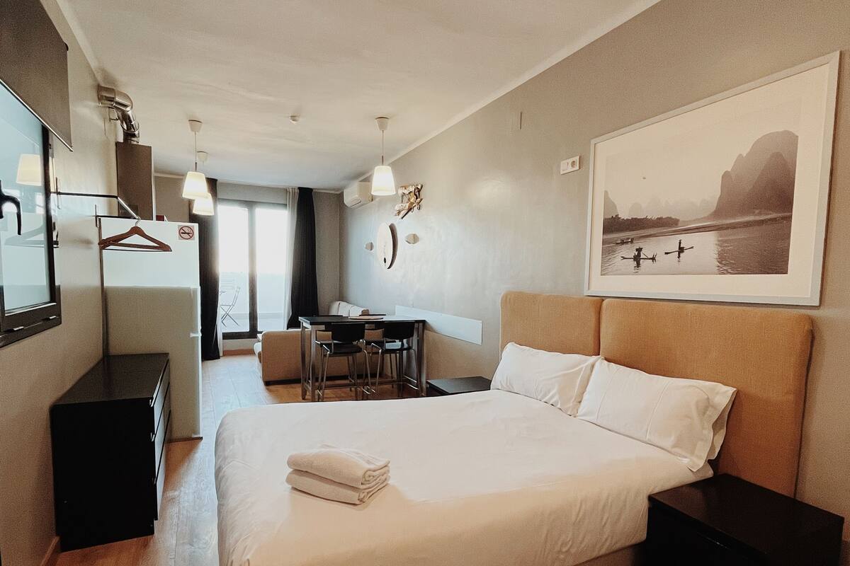 A modern hotel room with a large bed, a desk, and a chair.
