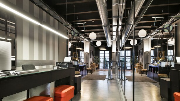 A modern office space with desks, chairs, and a central walkway.