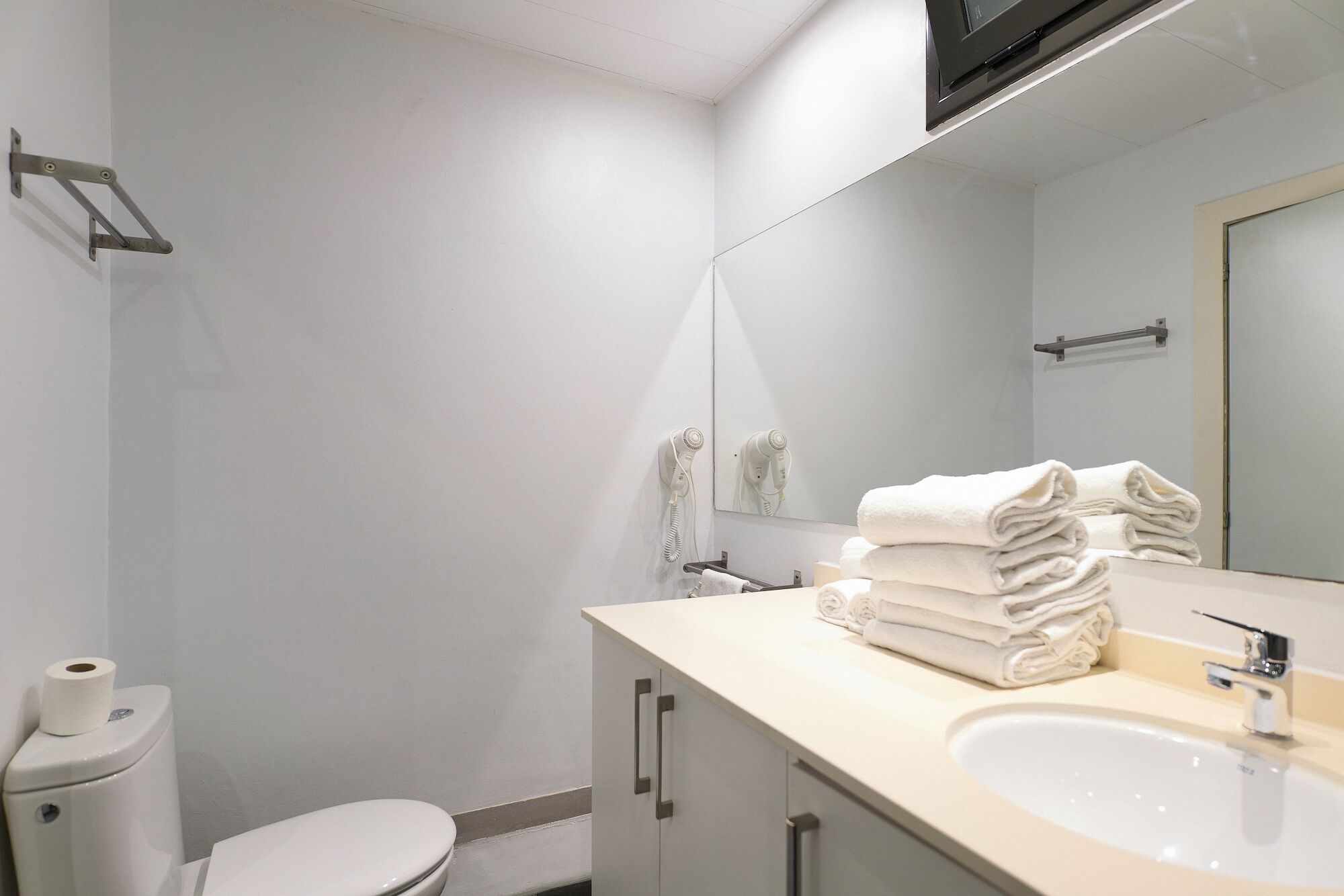 Un baño moderno con inodoro, lavamanos y una pila de toallas.