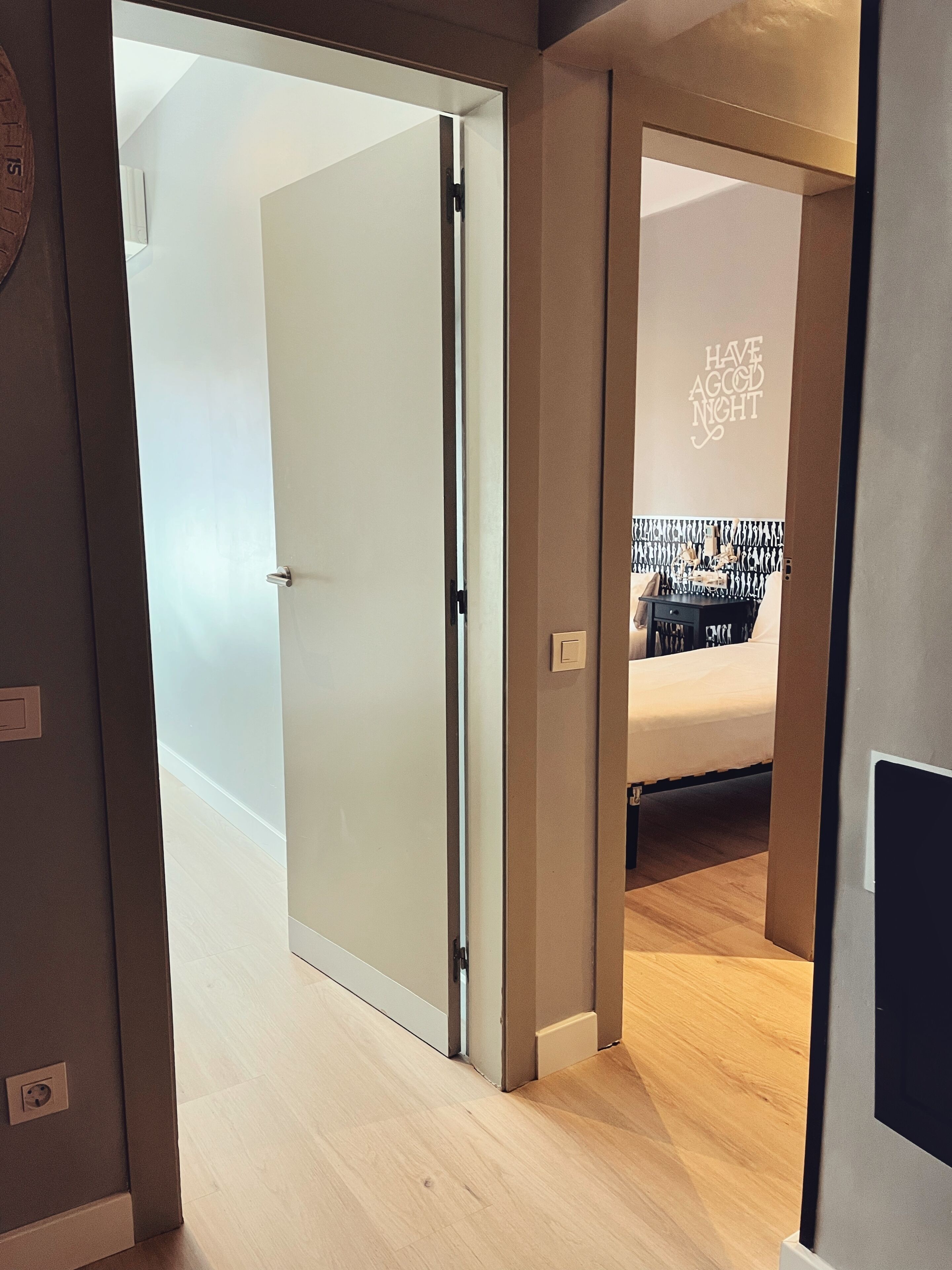 A modern hotel room with a bed, a bedside table, and a wall with a motivational quote.