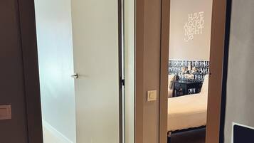 A modern hotel room with a bed, a bedside table, and a wall with a motivational quote.