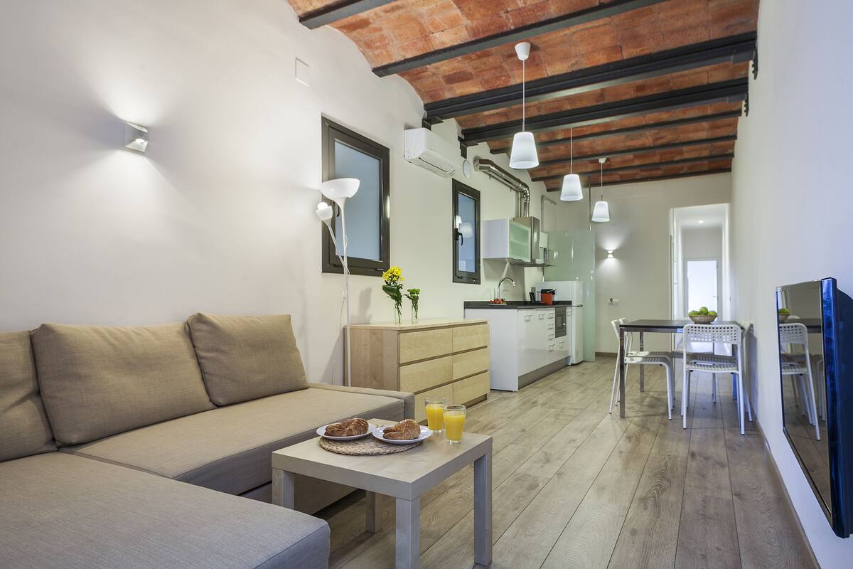 A modern living room with a sofa, dining table, and breakfast setup.