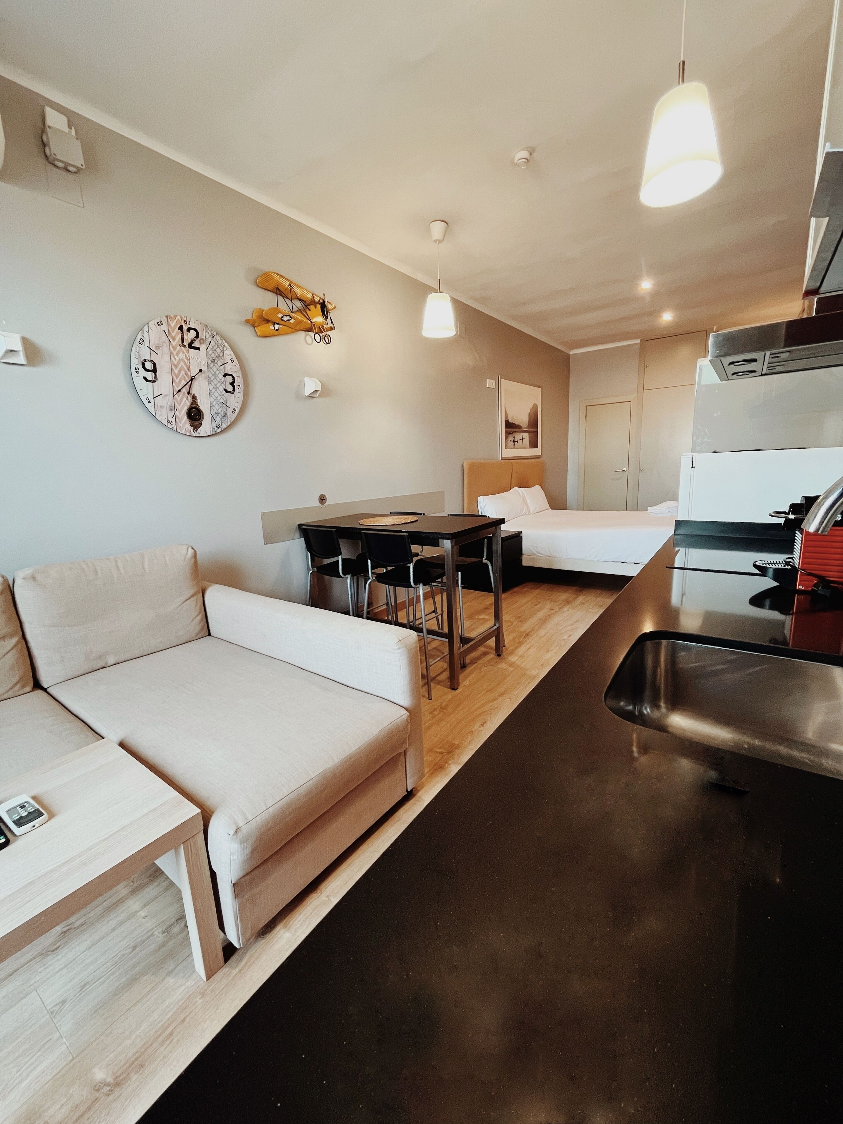 Un espace de vie moderne et bien éclairé, comprenant un canapé, une table à manger et un coin cuisine.