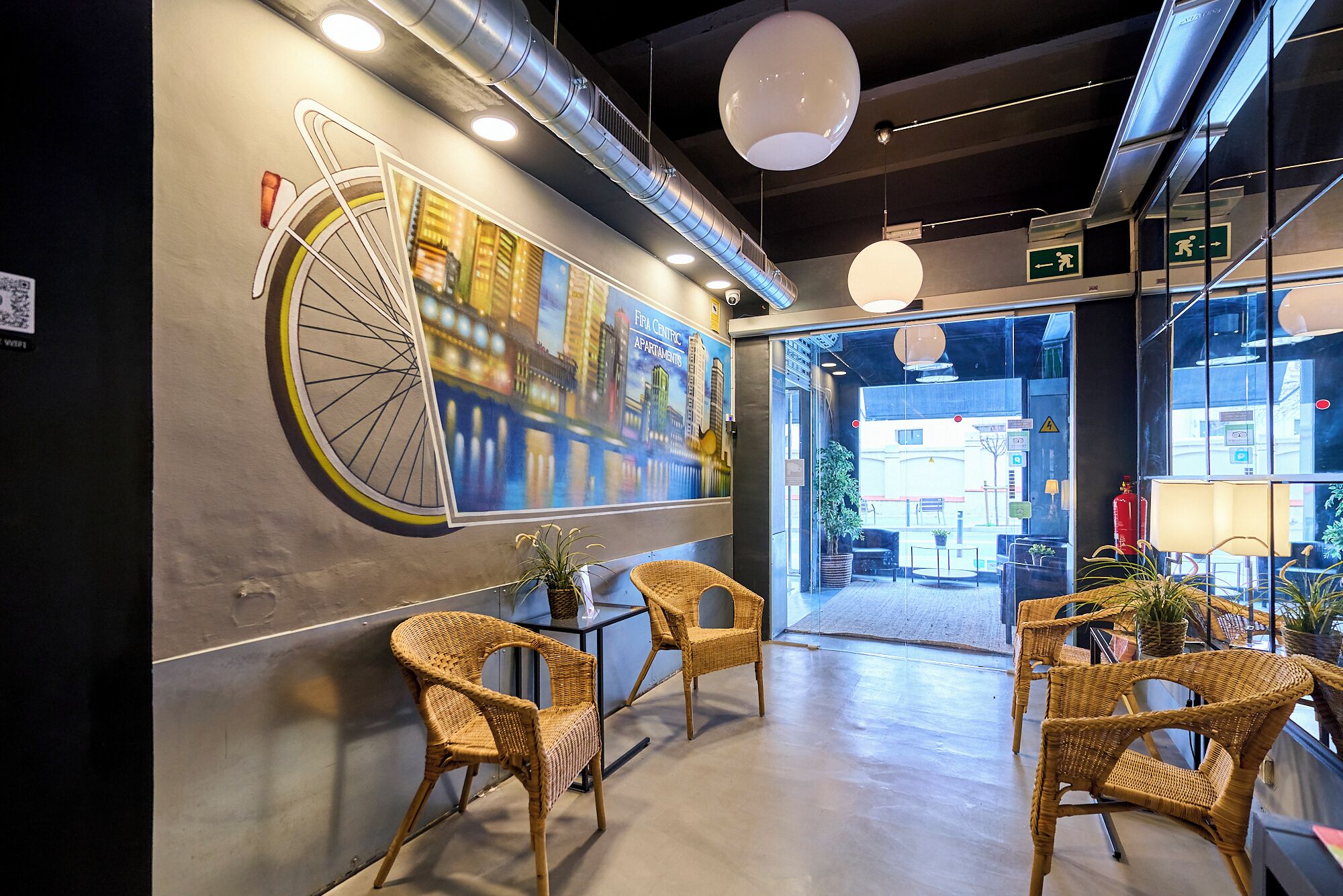 Ein modernes Interieur mit Korbstühlen, einer großen Fahrrad-Mural und Blick auf die Straße.