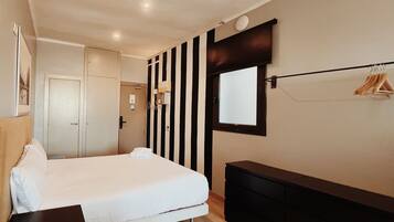 Un dormitorio moderno con cama, mesitas de noche, cómoda, espejo y perchero.