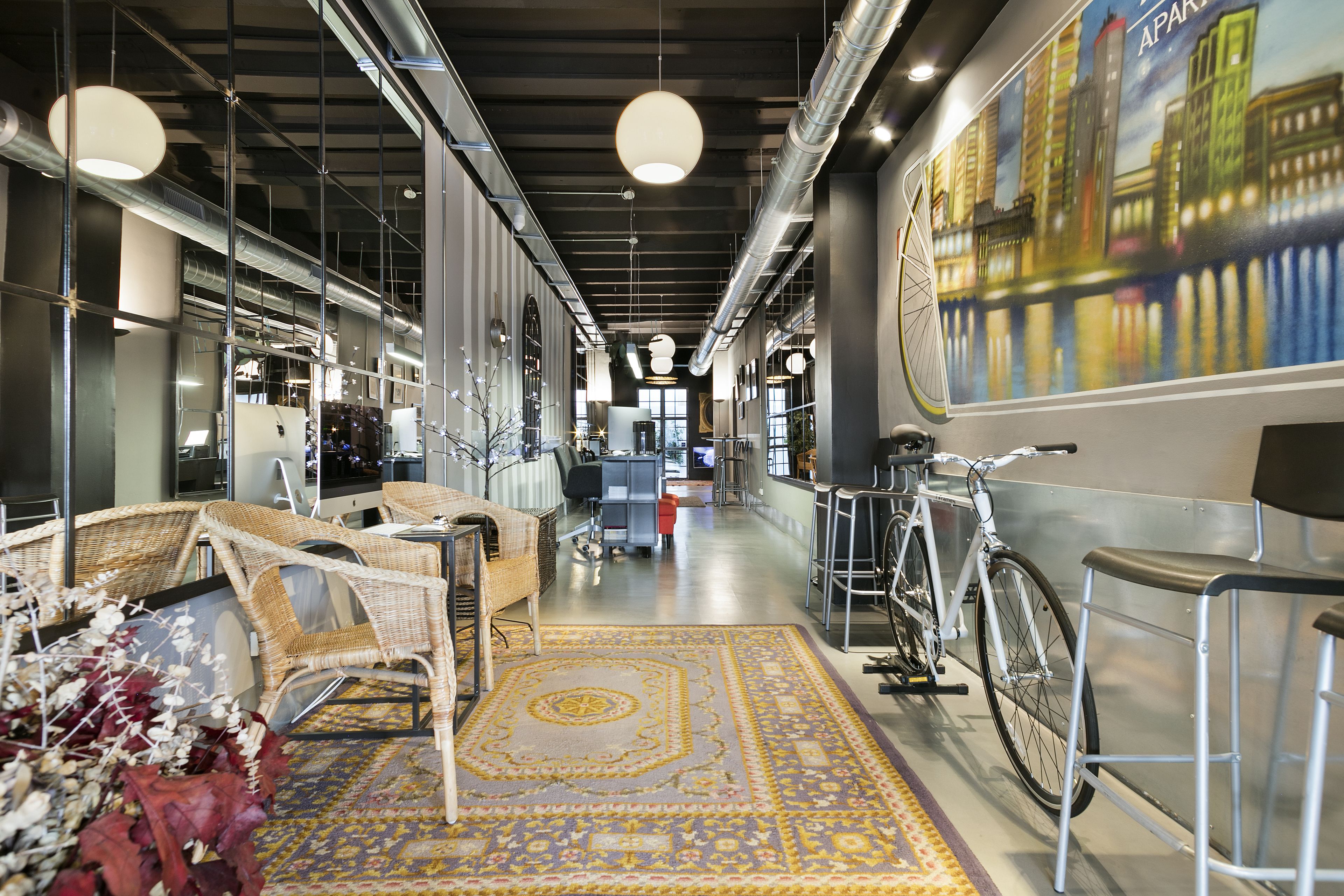 Een modern interieur met rieten meubels, een gekleurd tapijt en een fiets.