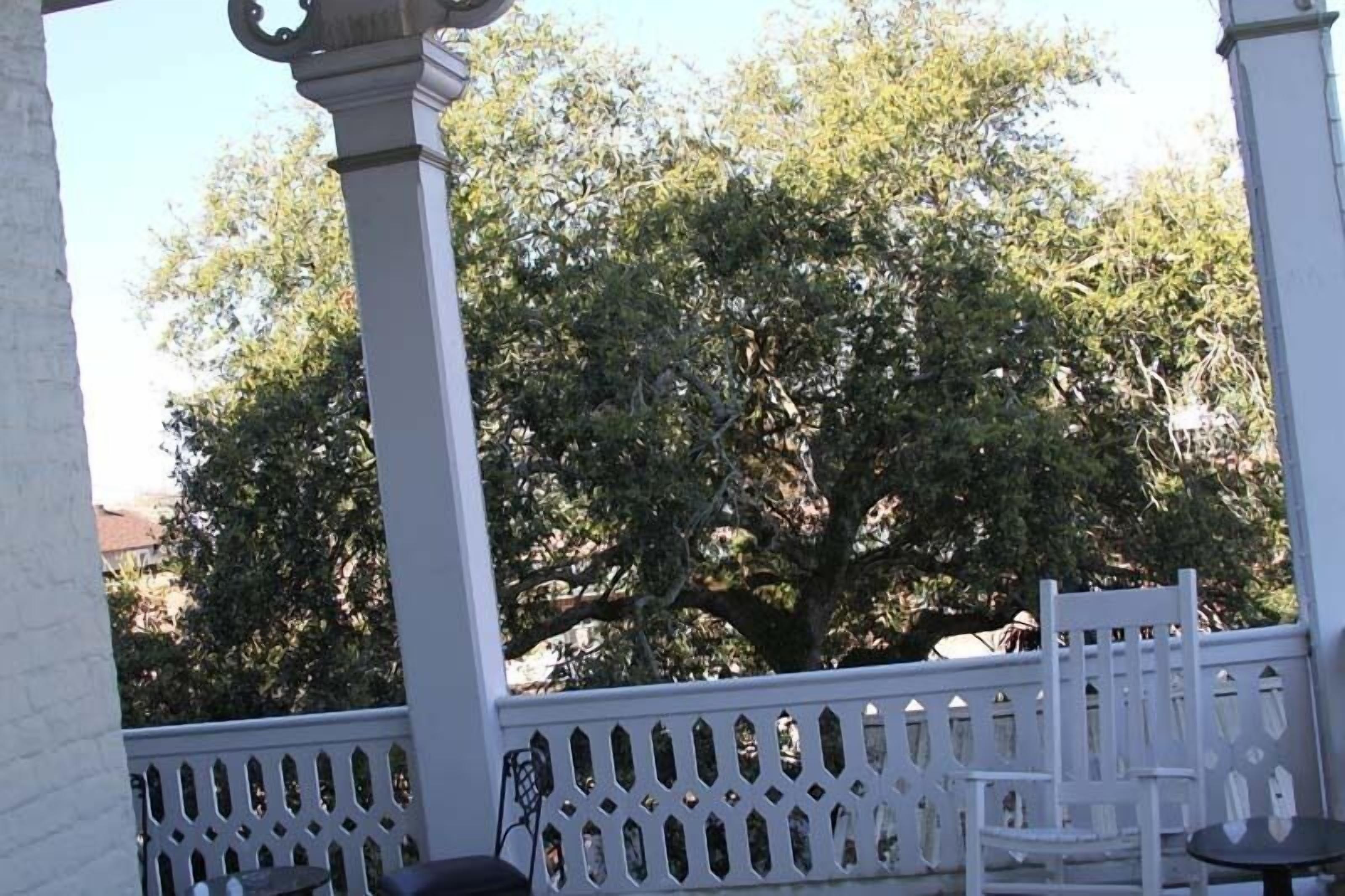 A covered outdoor area with white lattice railings, a white chair, and a small table.