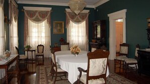 A dining room with a round table, chairs, and a chandelier. - The Dansereau House (Thibodaux)