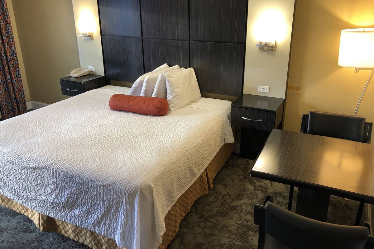 A hotel room with a large bed, bedside tables, a desk, and a chair.