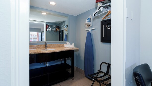 Une salle de bain avec un lavabo doté d’un plan de travail en granit, un miroir, un porte-serviettes et une chaise noire.