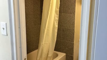 A bathroom with a bathtub, a shower curtain, and a toilet.