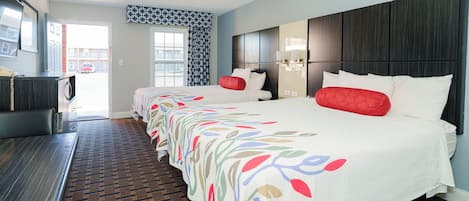 A hotel room with a large bed, a desk, and a view of the street.