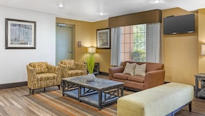 A living room with a sofa, armchairs, a coffee table, and a flat-screen TV mounted on the wall. - Best Western East El Paso Inn (Clint)