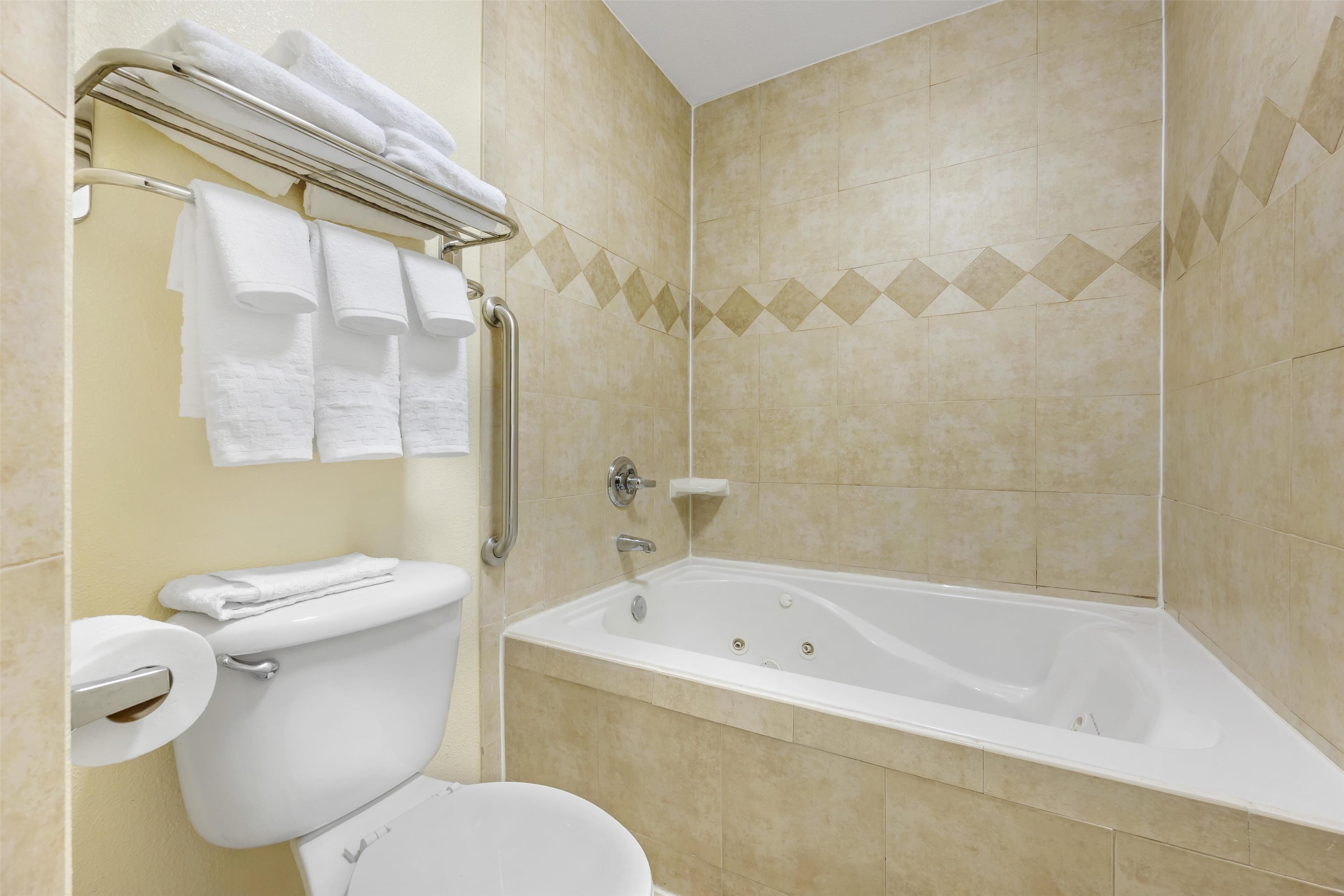 A bathroom with a toilet, a bathtub, and a towel rack with multiple towels.