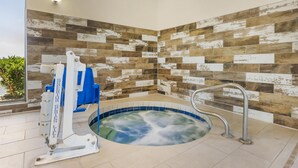 A spa area with a hot tub, a massage chair, and a wall with a rustic tile design. - Best Western East El Paso Inn (Clint)