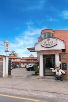 Entrada de hotel con un letrero que dice 'Kuna Hotel', una figura de mascota y un área de estacionamiento.