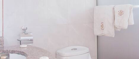 A bathroom with a toilet, sink, and a glass shower door.