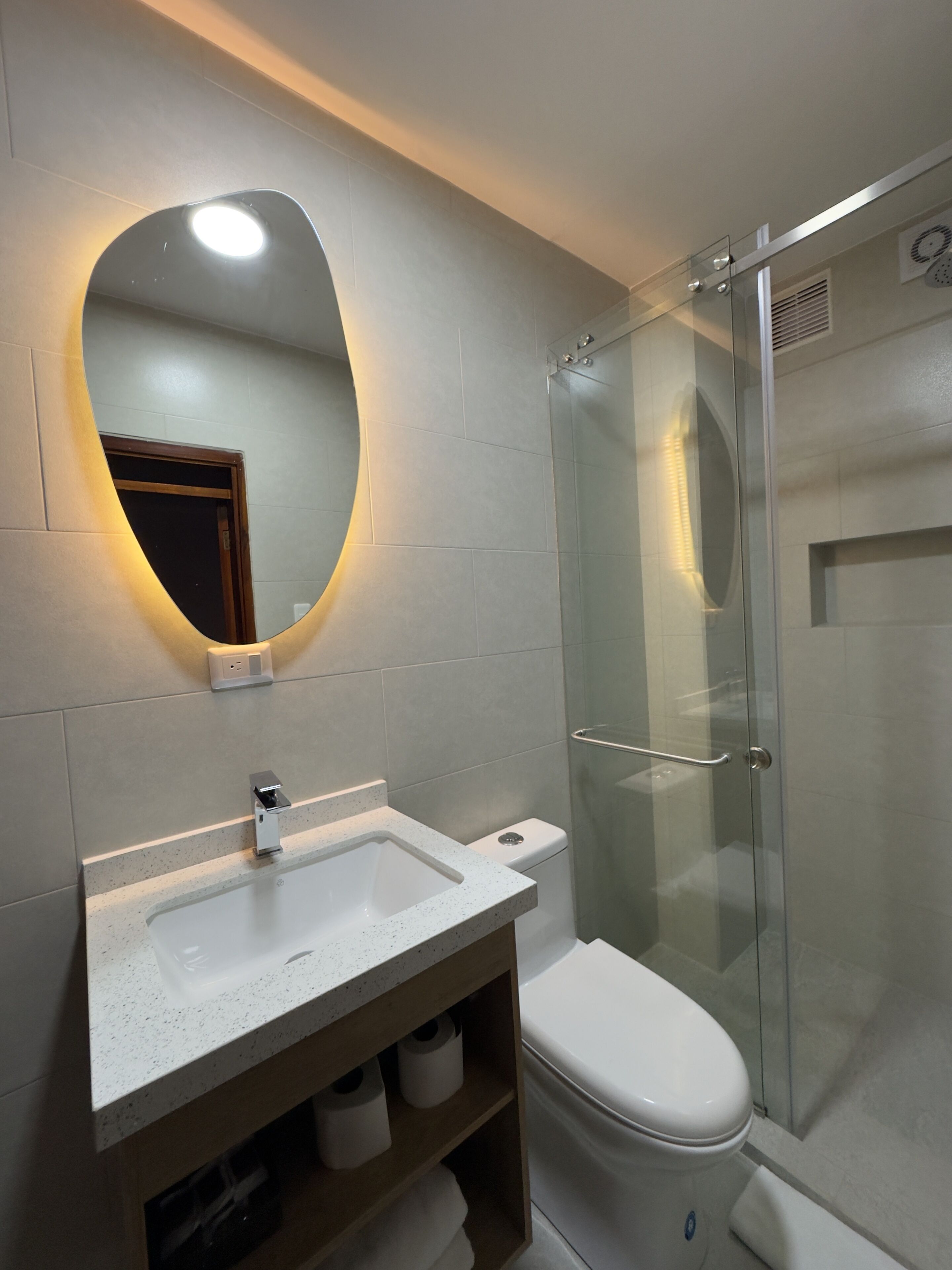 A bathroom with a white sink, a toilet, and a glass shower enclosure.