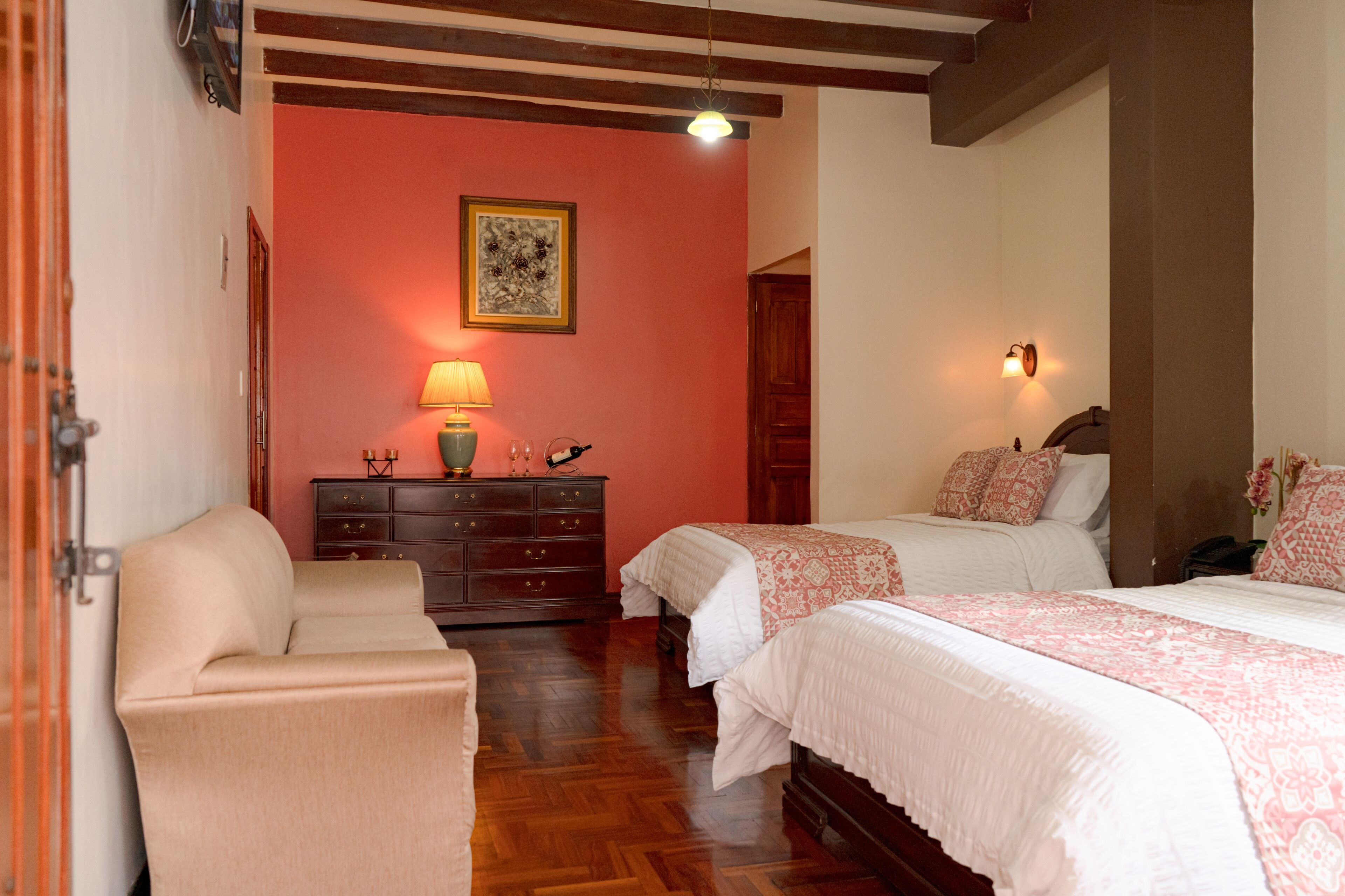A bedroom with two beds, a dresser, a chair, and a lamp.