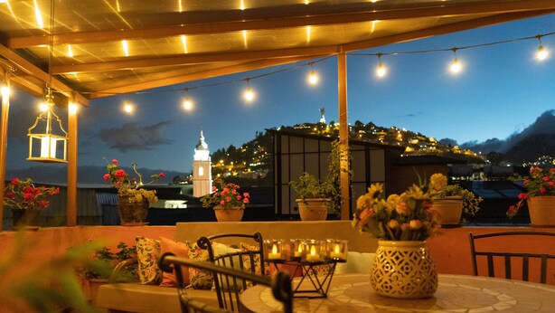 An outdoor patio with a table set for dining, surrounded by potted plants and string lights. - Rincón Familiar Hotel Boutique (Quito)
