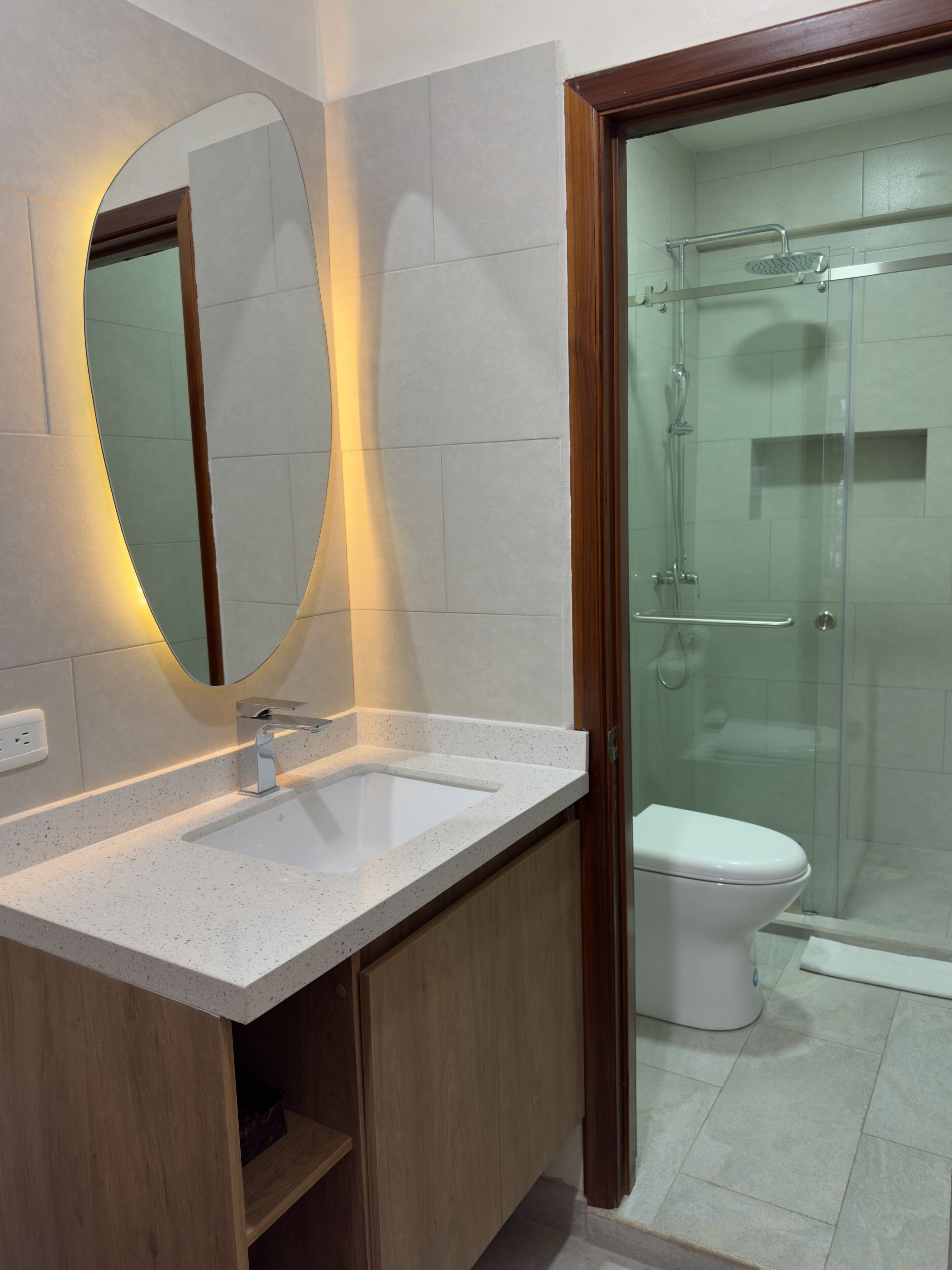 A bathroom with a white sink, a mirror, and a glass shower enclosure.