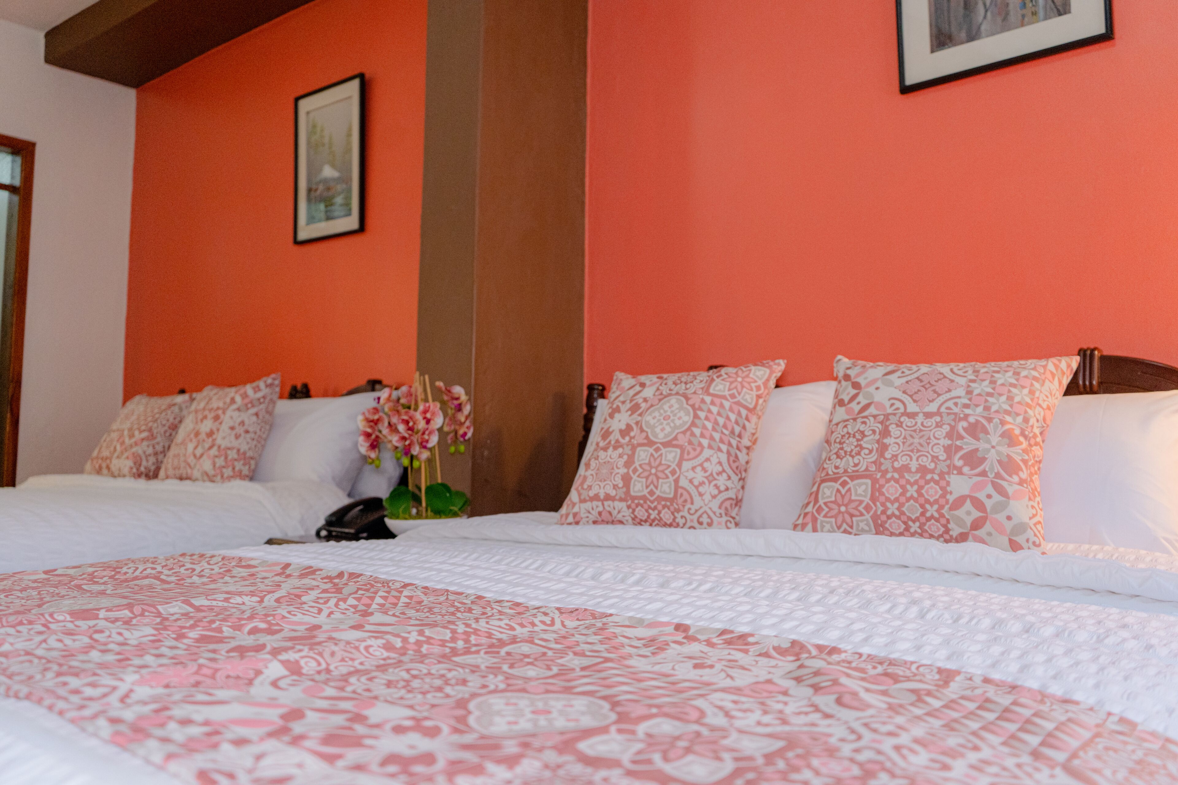 A hotel room with a large bed, orange walls, and a framed picture on the wall.