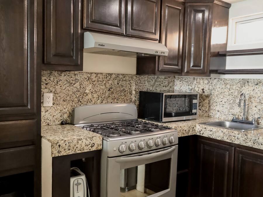 Una cocina con armarios de madera oscura, una estufa de acero inoxidable, un microondas y un fregadero.