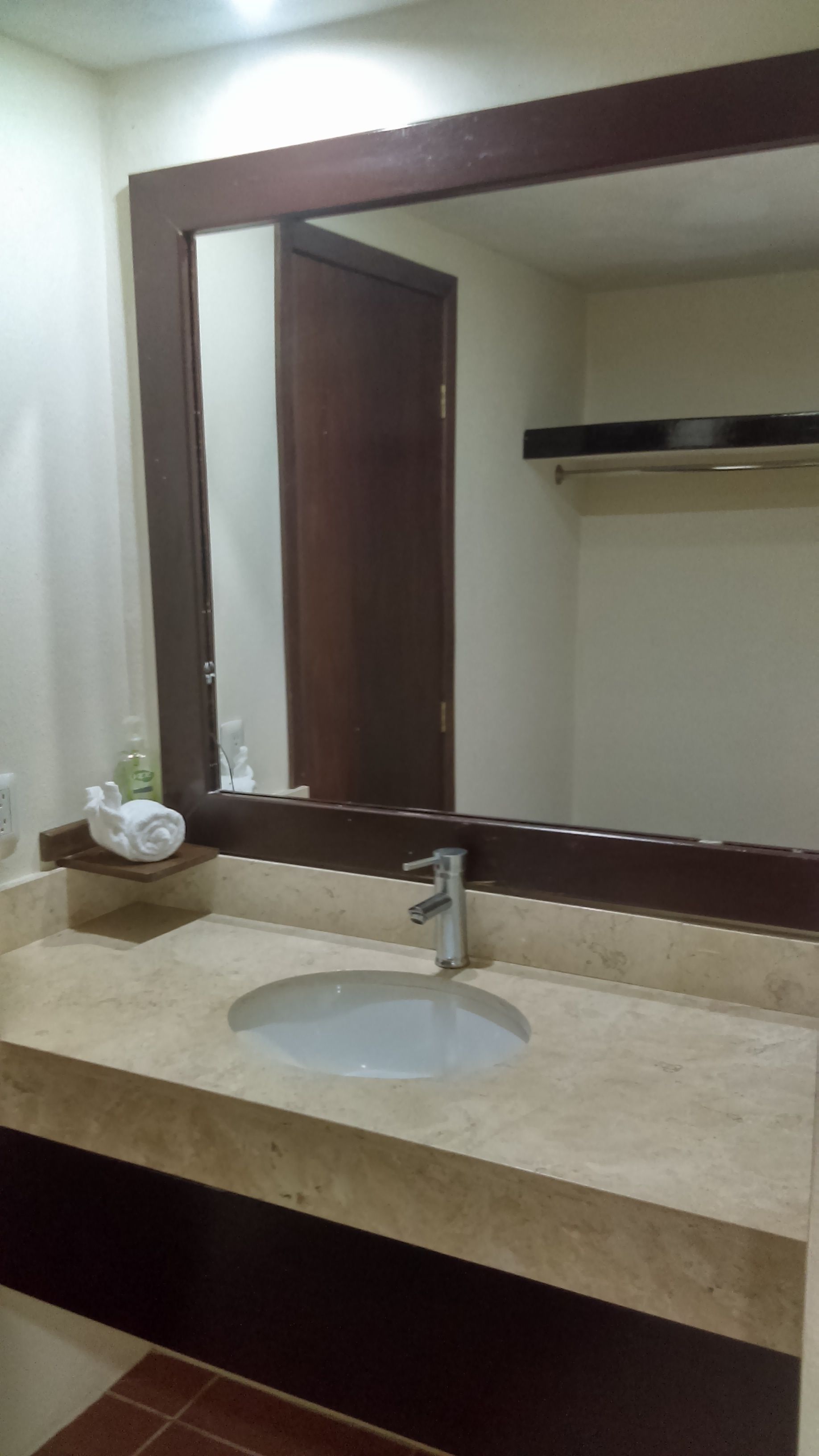 A bathroom with a sink, mirror, and towel rack.