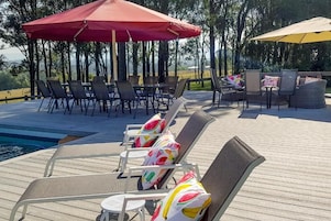 Una piscina al aire libre, sombrillas, sillones reclinables de piscina