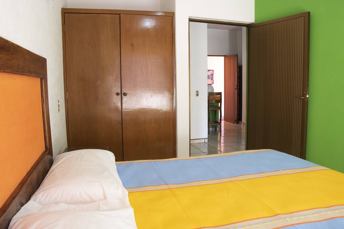Een slaapkamer met een bed, een kledingkast en een groene wand.