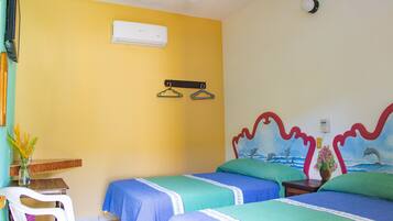Habitación de hotel con dos camas, una mesita, una silla, un equipo de aire acondicionado y un mural en la pared.