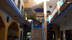 A multi-level interior with a central staircase, arched doorways, and a mix of open and enclosed spaces. - Hotel Bahía (San Patricio Melaque)