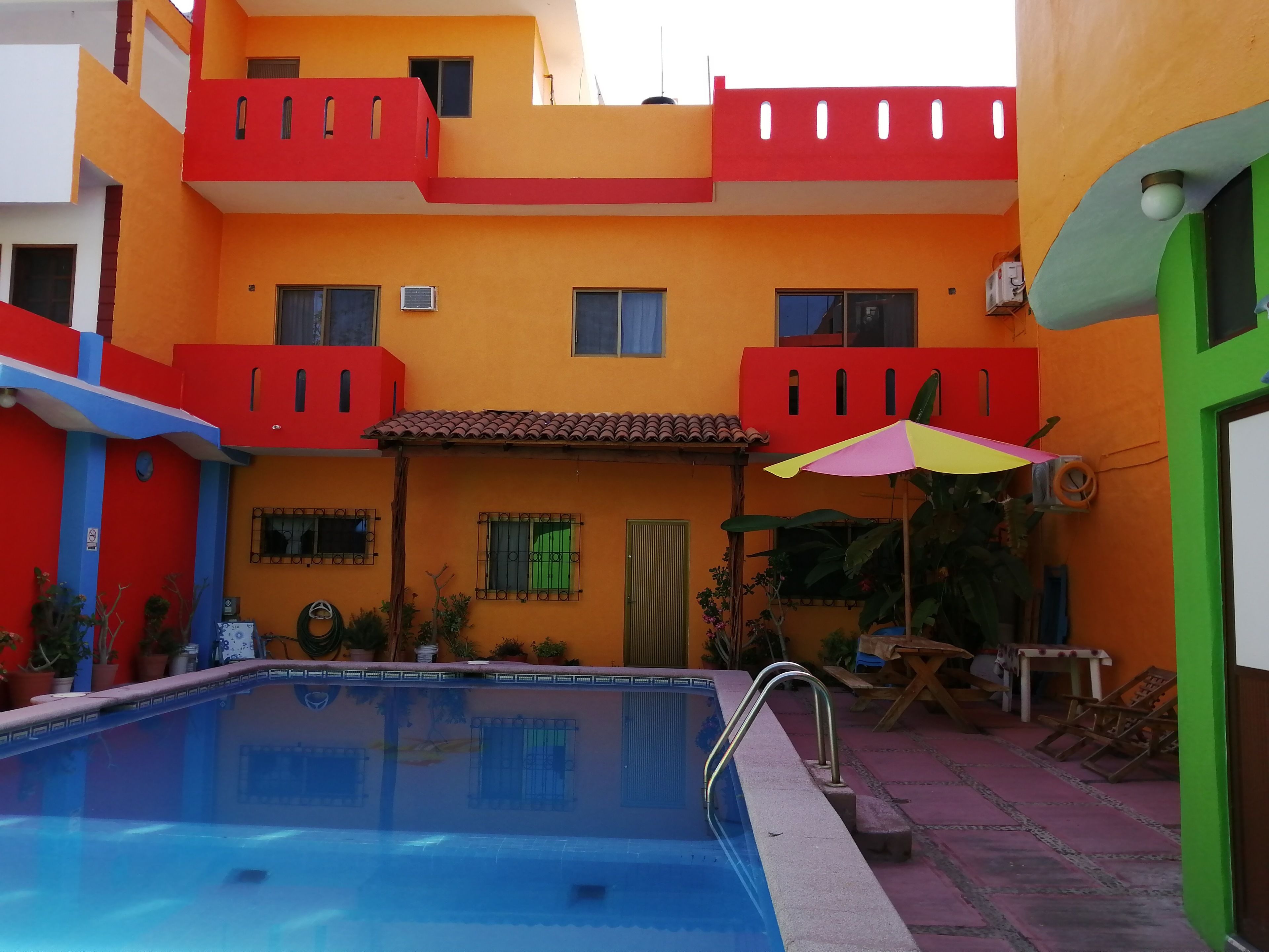 A swimming pool with a red and yellow building in the background.