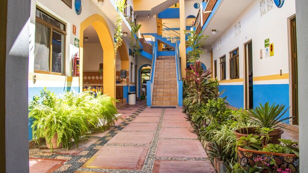 A narrow corridor with a central staircase, flanked by balconies with potted plants and a tiled floor. - Hotel Bahía (San Patricio Melaque)