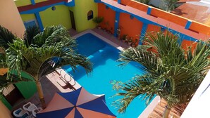 A pool area with a blue pool, surrounded by colorful walls and potted plants. - Hotel Bahía (San Patricio Melaque)