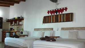 Habitación de hotel con dos camas, kitchenette, microondas y un adorno decorativo en la pared.