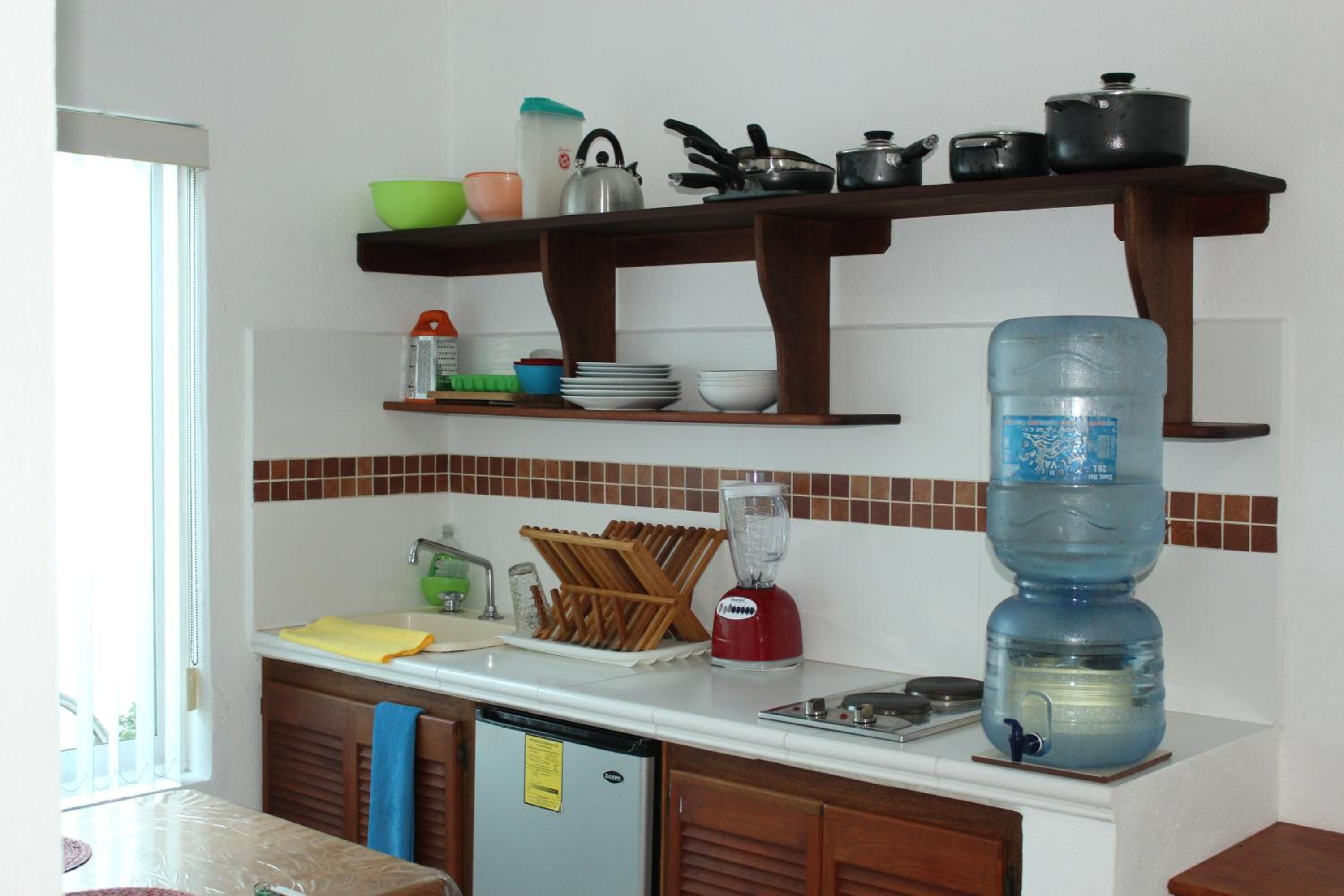 Una cocina con dispensador de agua, batidora y varios utensilios de cocina sobre la encimera.